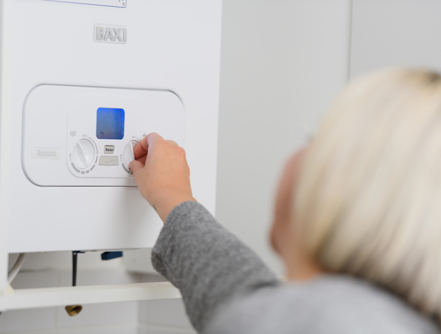 A woman changing the settings on her boiler