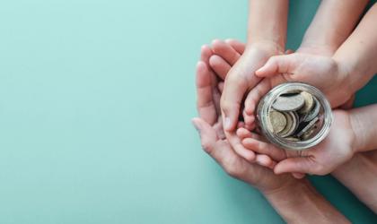 A family of hands holding a jar of money