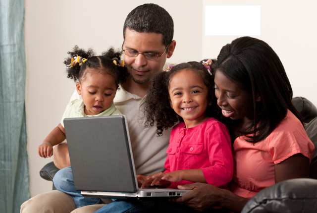 A family at home looking at a laptop and smiling