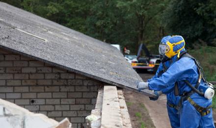 2 people in protective suits looking at a roof