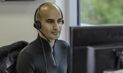 A Midland Heart employee with a headset, looking at the computer