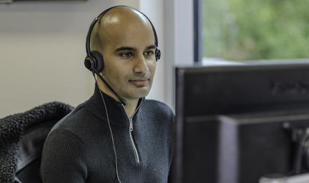 A Midland Heart employee with a headset, looking at the computer