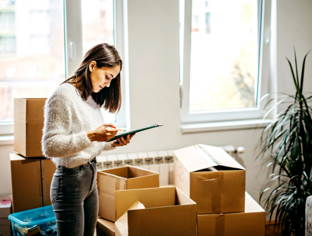 A woman standing with a checklist as she packs boxes