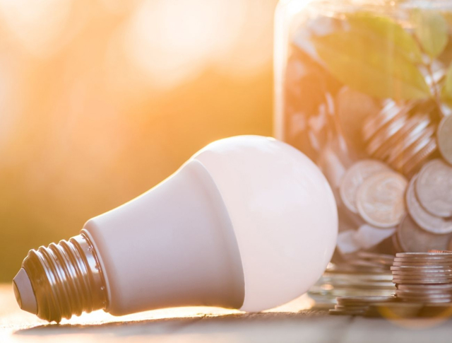 A lightbulb next to a jar of coins