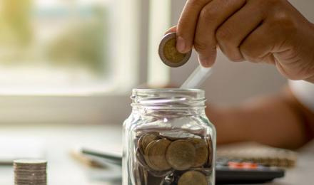 A person saving money in a jar