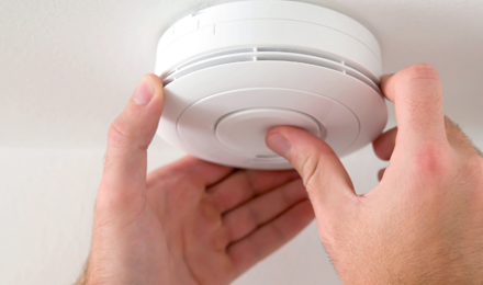 Person pushing the button of a smoke alarm