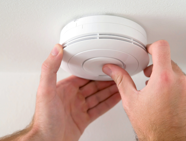 Person pushing the button of a smoke alarm