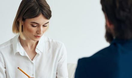 Woman speaking to someone while writing on a clipboard