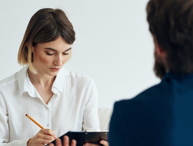 Woman speaking to someone while writing on a clipboard