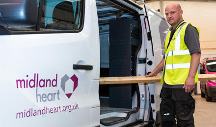 An employee standing next to a Midland Heart van