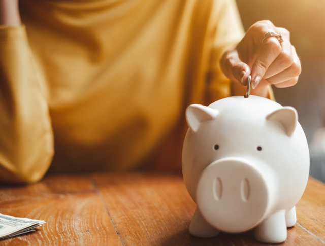 A person putting a coin in a piggy bank