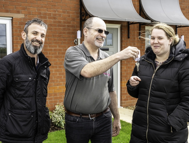 A tenant receiving the new key to their home from a Midland Heart employee