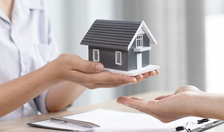 A person holding a miniature home to symbolise selling your home