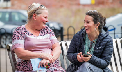 A tenant sitting on a bench speaking to a Midland Heart employee