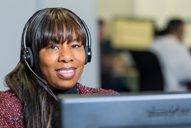 A Midland Heart employee wearing a headset at their desk and computer