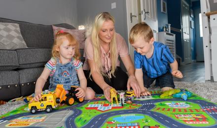 A woman playing her children on the floor